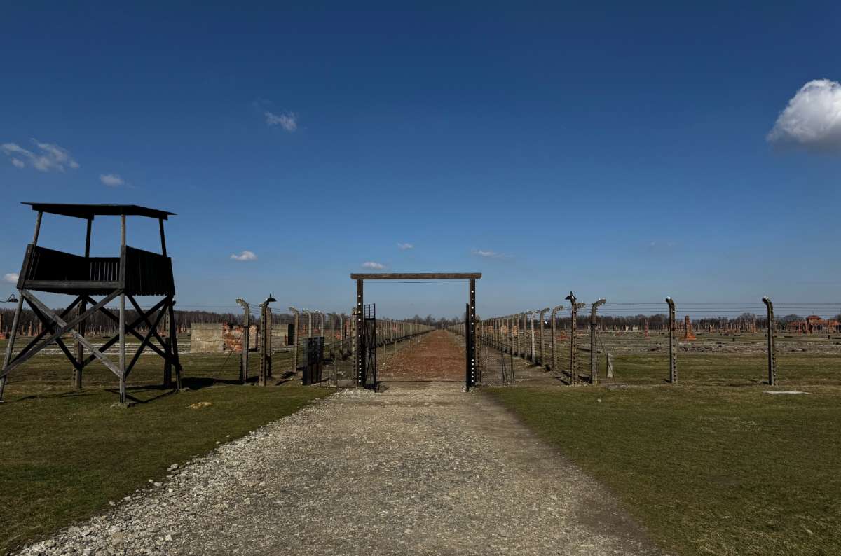 a photo of an entry to the Auschwitz concentration camp, showing the entry gate and lots of barbed wire, Oświęcim, Poland, photo by Next Level of Travel