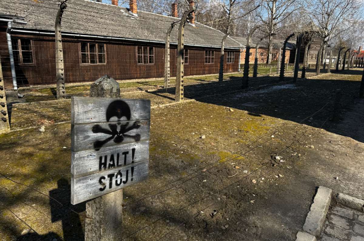 a photo of the outside of the wooden barracks and a stop sign on the lawn in front of them, forbidding entry, Oświęcim, Poland, photo by Next Level of Travel