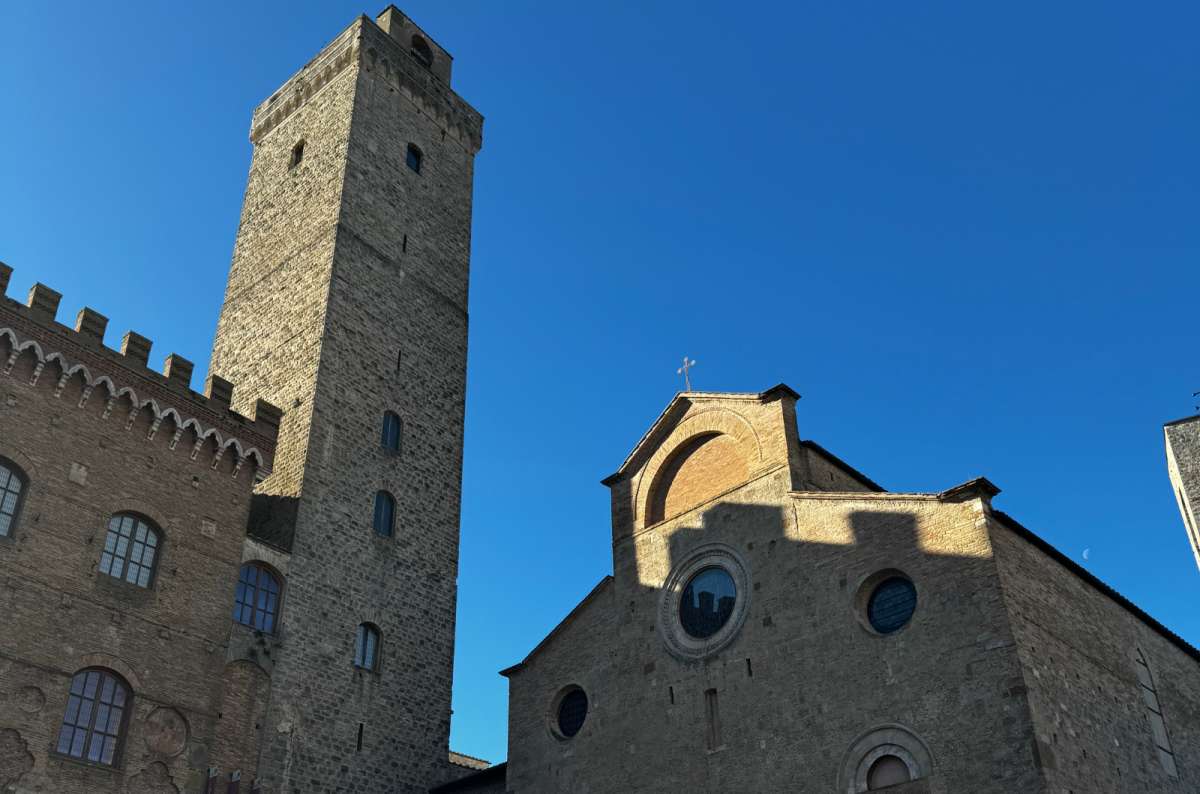 a photo of the view in Piazza del Duomo focused on Duomo di San Gimignano and Torrw Grossa, Italy, photo by Next Level of Travel