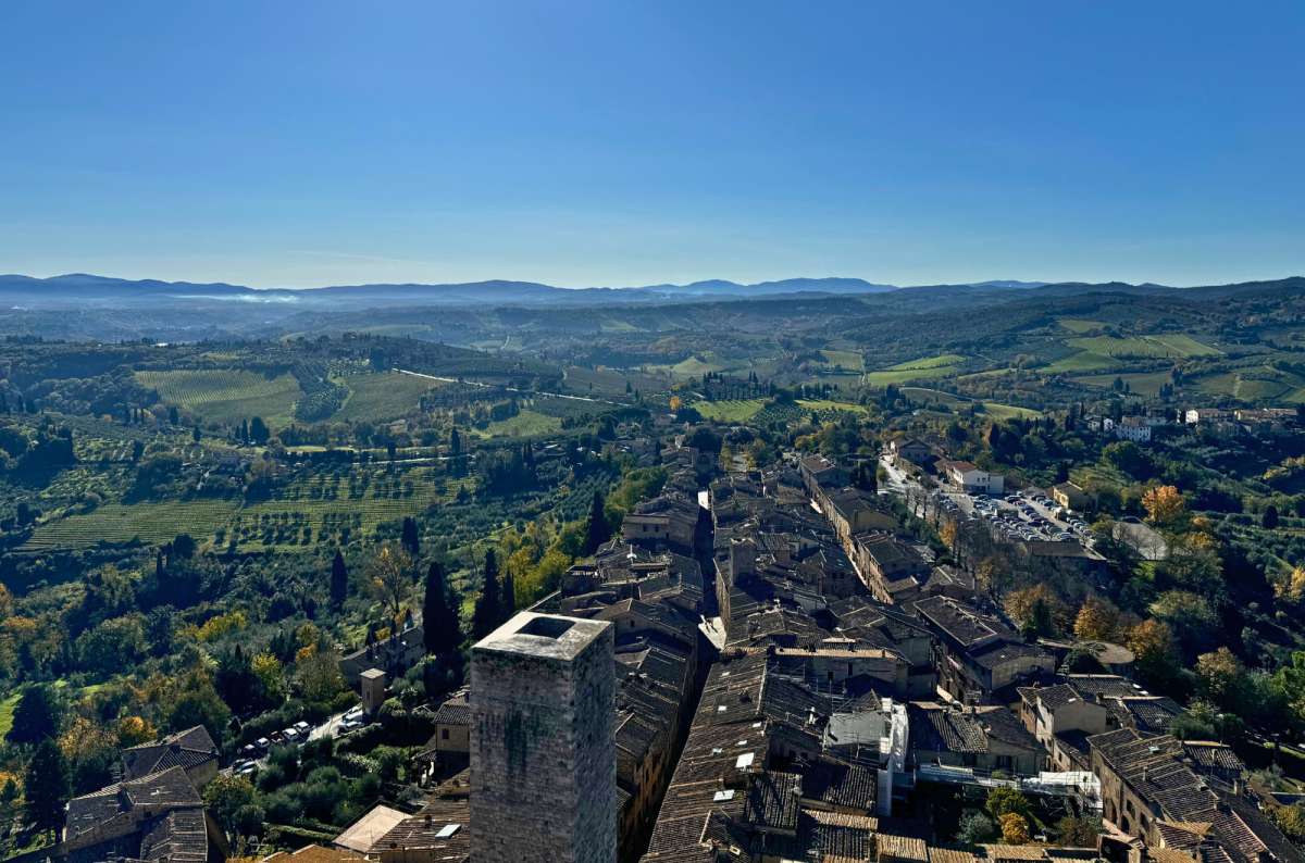 a photo of the view of San Gimignano with a parking lot visible in the far background, outside the city gates, Italy, photo by Next Level of Travel