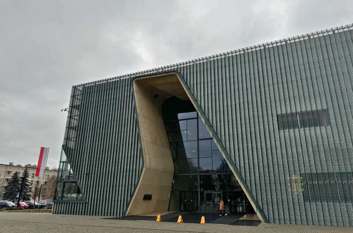 Exterior view of the POLIN Museum of the History of Polish Jews in Warsaw, Poland, showcasing its modern architecture with a wavy glass and stone façade, photo by Next Level of Travel