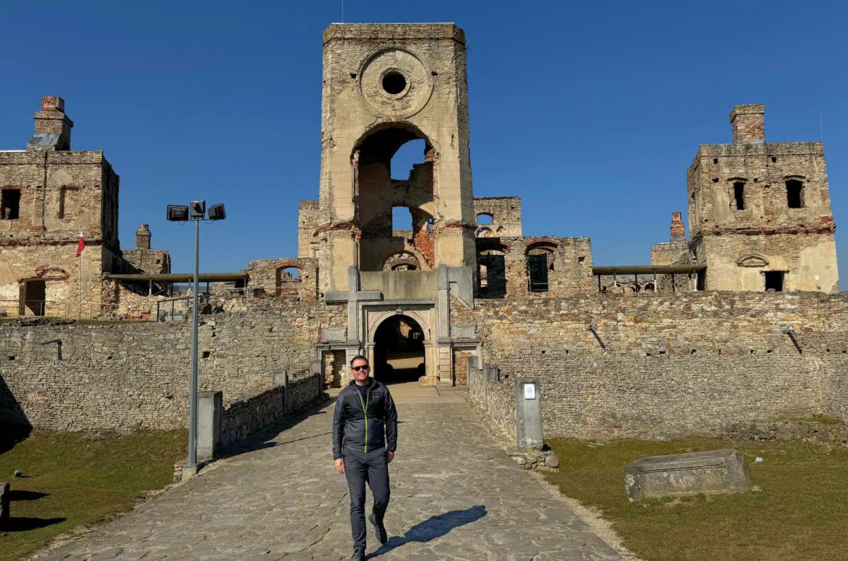 Traveler standing in front of the ruins of Krzyżtopór Castle under a clear blue sky in Ujazd, near Lublin, Poland, photo by Next Level of Travel
