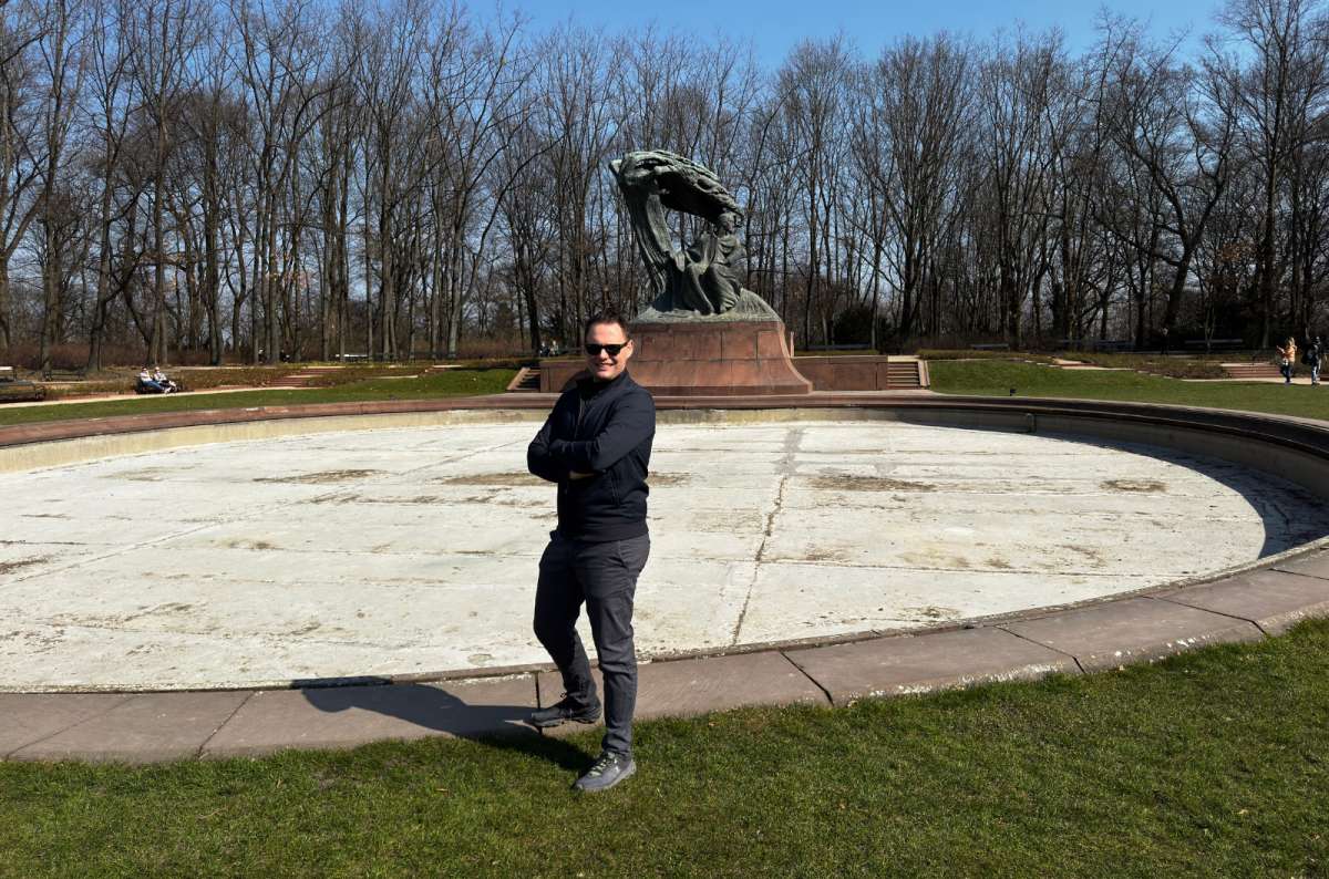 Visitor posing in front of the Fryderyk Chopin Monument at Łazienki Park in Warsaw, Poland, photo by Next Level of Travel