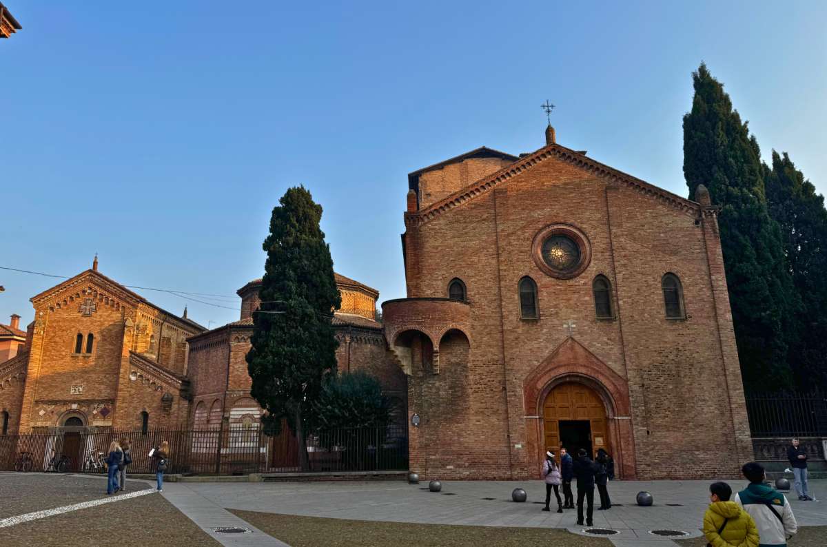 Exterior of Basilica di Santo Stefano in Bologna, Italy, with people walking in the square in front, photo by Next Level of Travel, bologna worth visiting