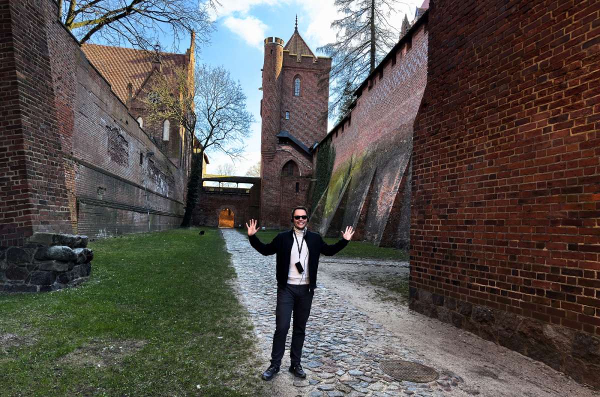 Traveler standing inside the brick walls of Malbork Castle, exploring the medieval courtyards and towers, another reason why is Malbork Castle worth visiting, photo by Next Level of Travel