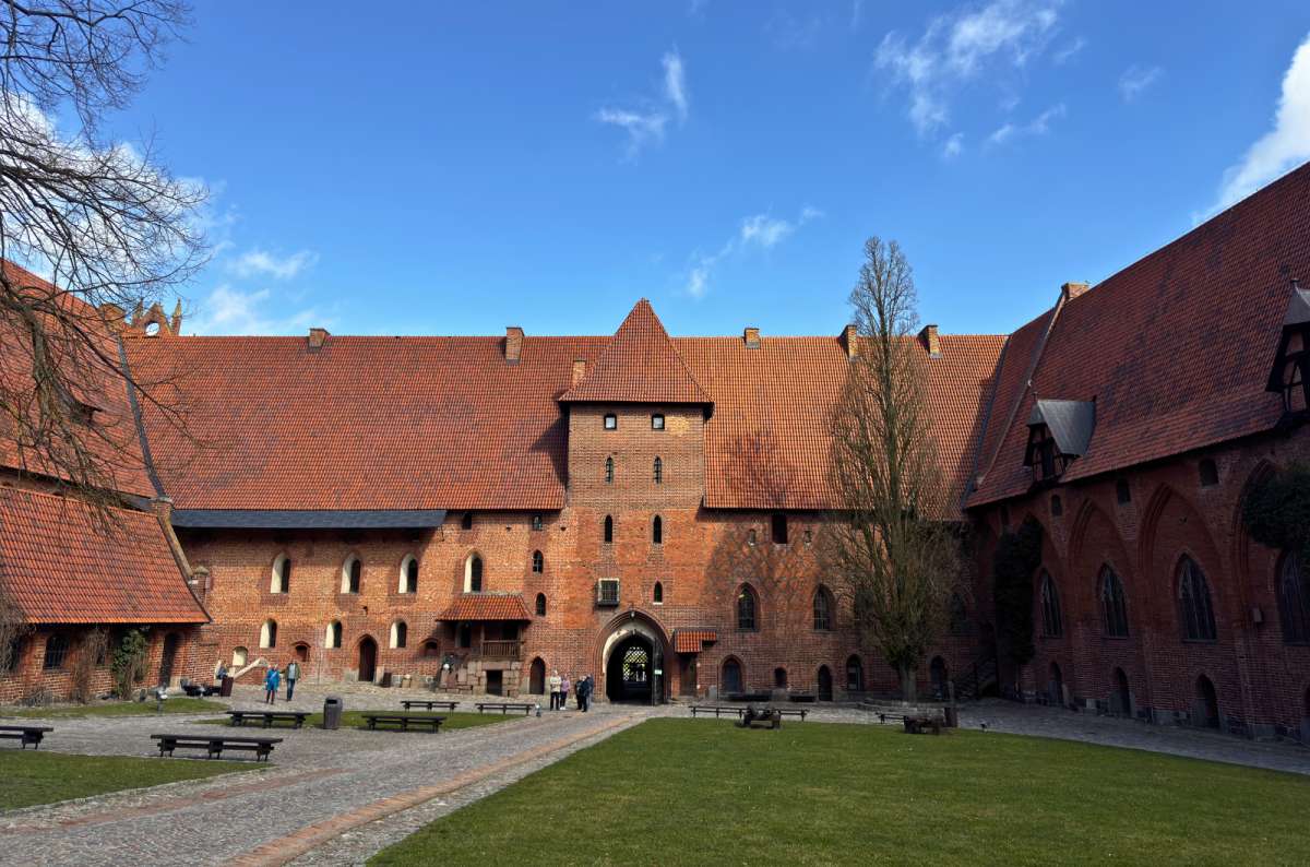 Wide view of the inner courtyard and brick buildings of Malbork Castle in Malbork, Poland, former seat of Polish kings, photo by Next Level of Travel