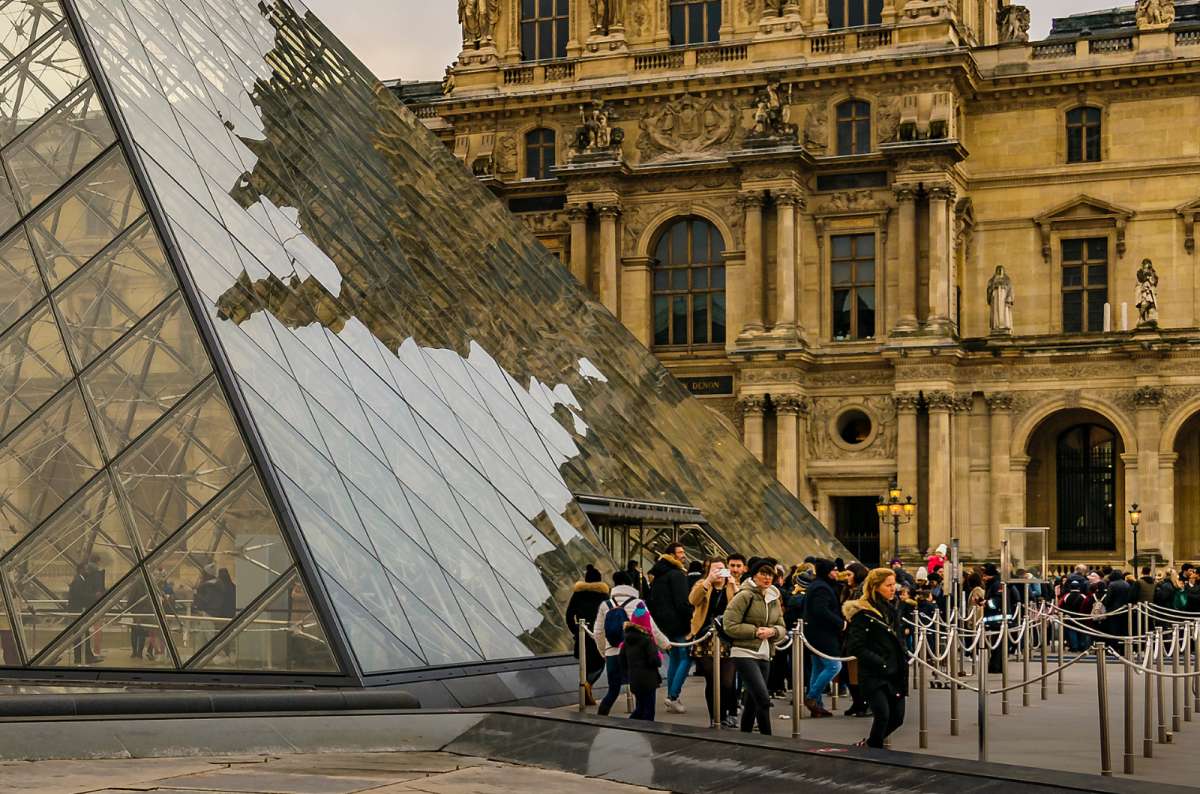 Glass pyramid entrance at the Louvre Museum with crowds lining up, Paris, France