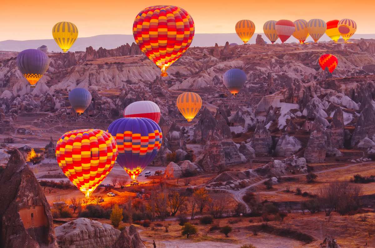 Hot air balloons floating over fairy chimneys at sunrise in Cappadocia, Turkey