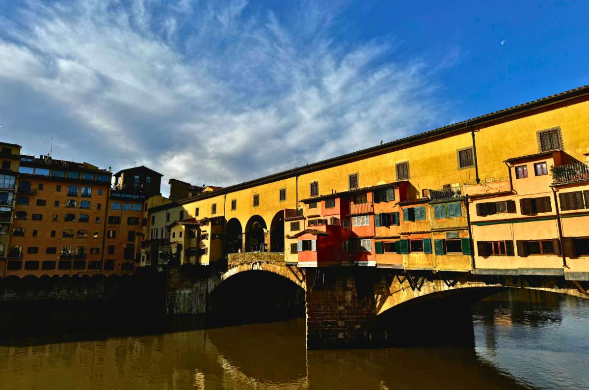 Ponte Vecchio bridge over the Arno River in Florence, Italy, one of the most famous tourist places in Europe with historic buildings lining the crossing, photo by Next Level of Travel