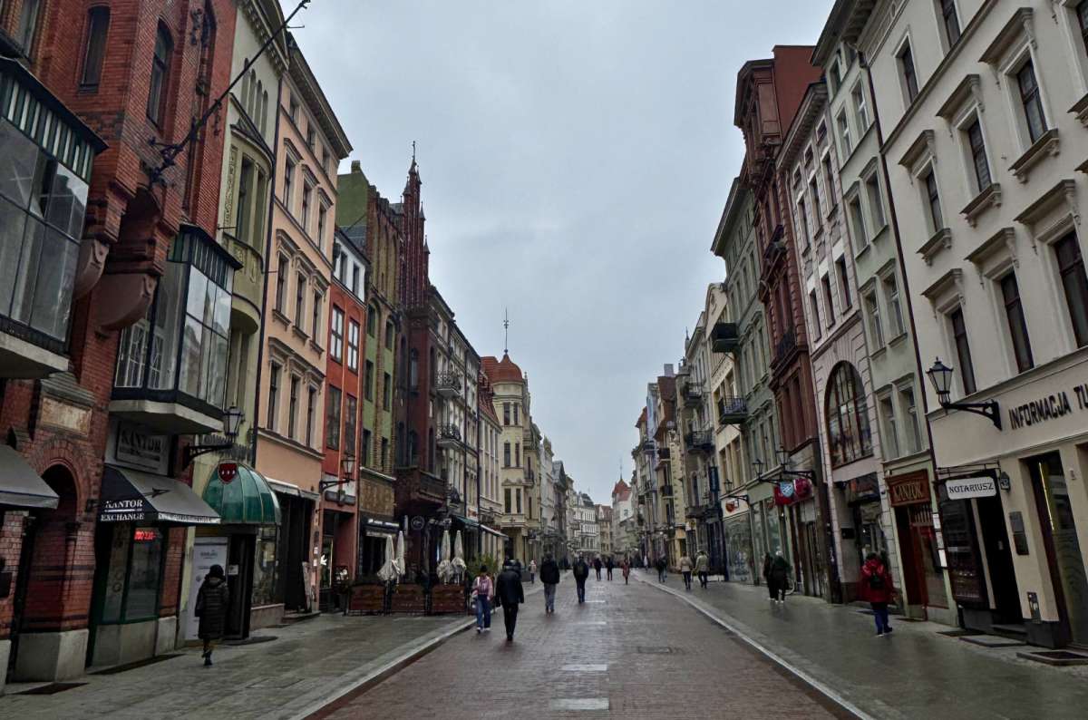 Szeroka Street in Toruń, Poland lined with colorful historic townhouses and pedestrian walkway, photo by Next Level of Travel