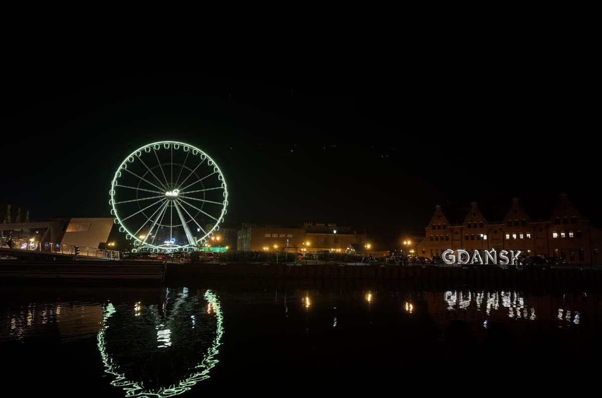 Ferris wheel and illuminated GDANSK sign reflected in the Motława River at night in Gdansk, Poland, photo by Next Level of Travel
