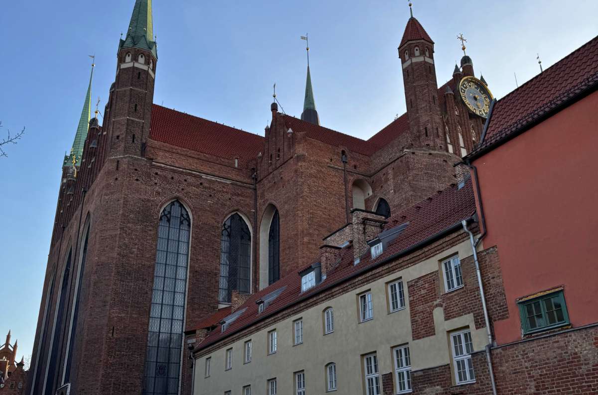 St. Mary’s Church (Bazylika Mariacka) in Gdansk Old Town, Poland, towering above surrounding townhouses, photo by Next Level of Travel