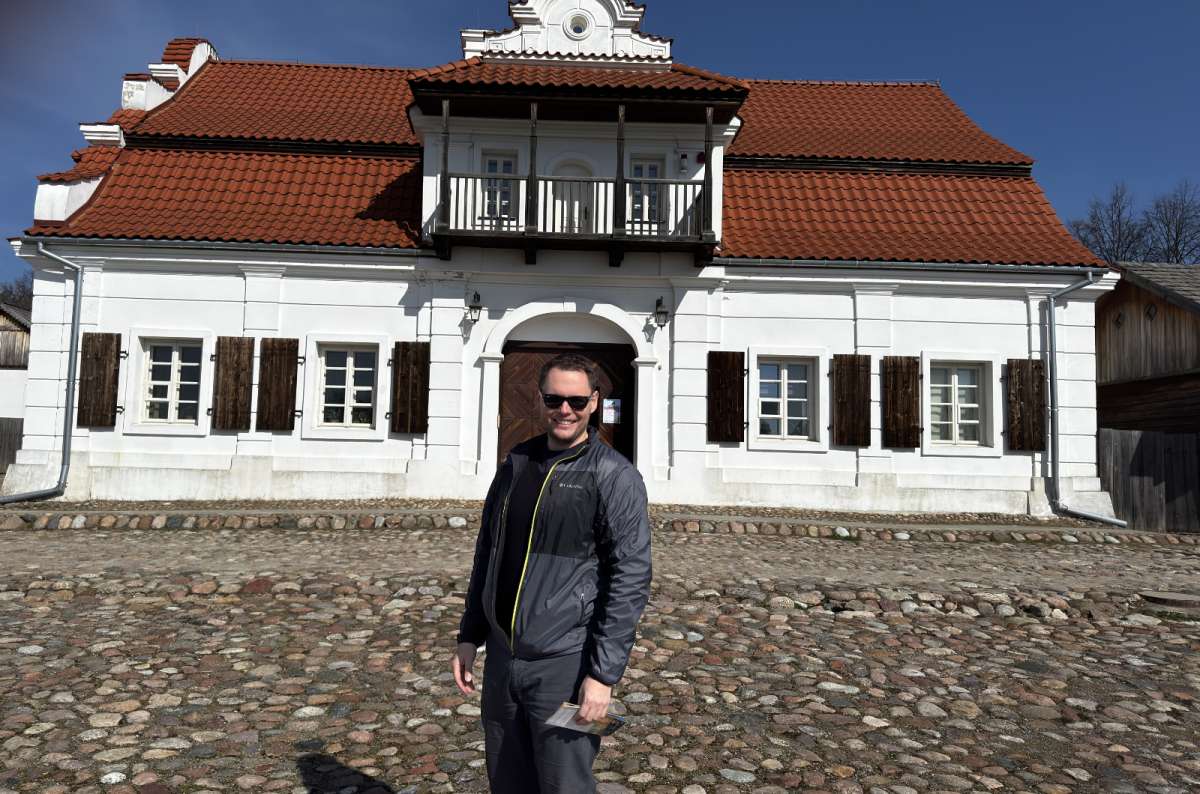 a photo of a tourist posing in front of a house that is part of the Lublin Outdoor Village Museum, Poland, photo by Next Level of Travel