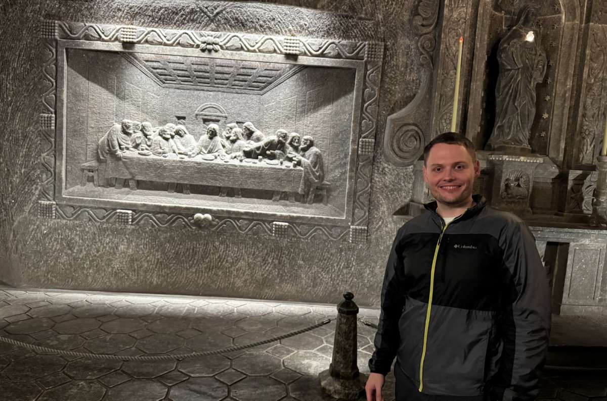 a photo of a tourist posing in front of the exhibition showing the Last Supper made out of salt in Wieliczka Salt Mine, Krakow, museum in Poland, photo by Next Level of Travel