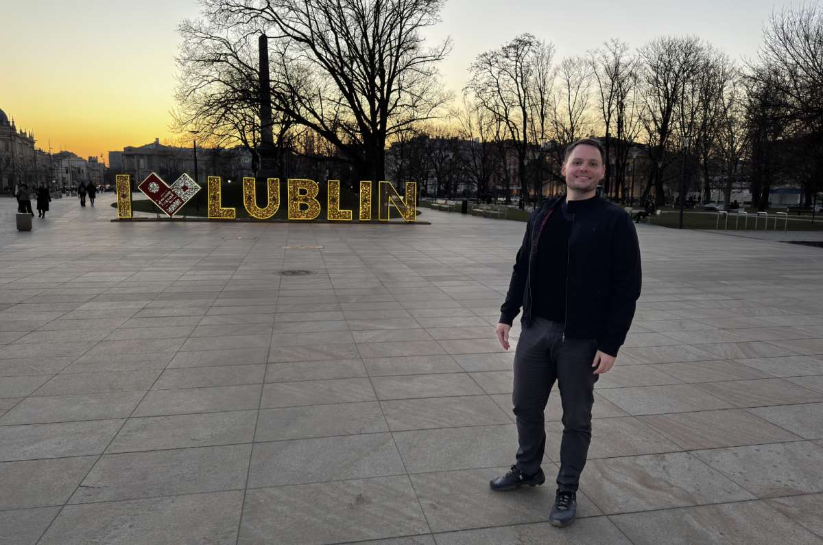 a photo of a tourist in Lublin posing in front of a glowing sign that says “I <3 Lublin”, Poland, photo by Next Level of Travel