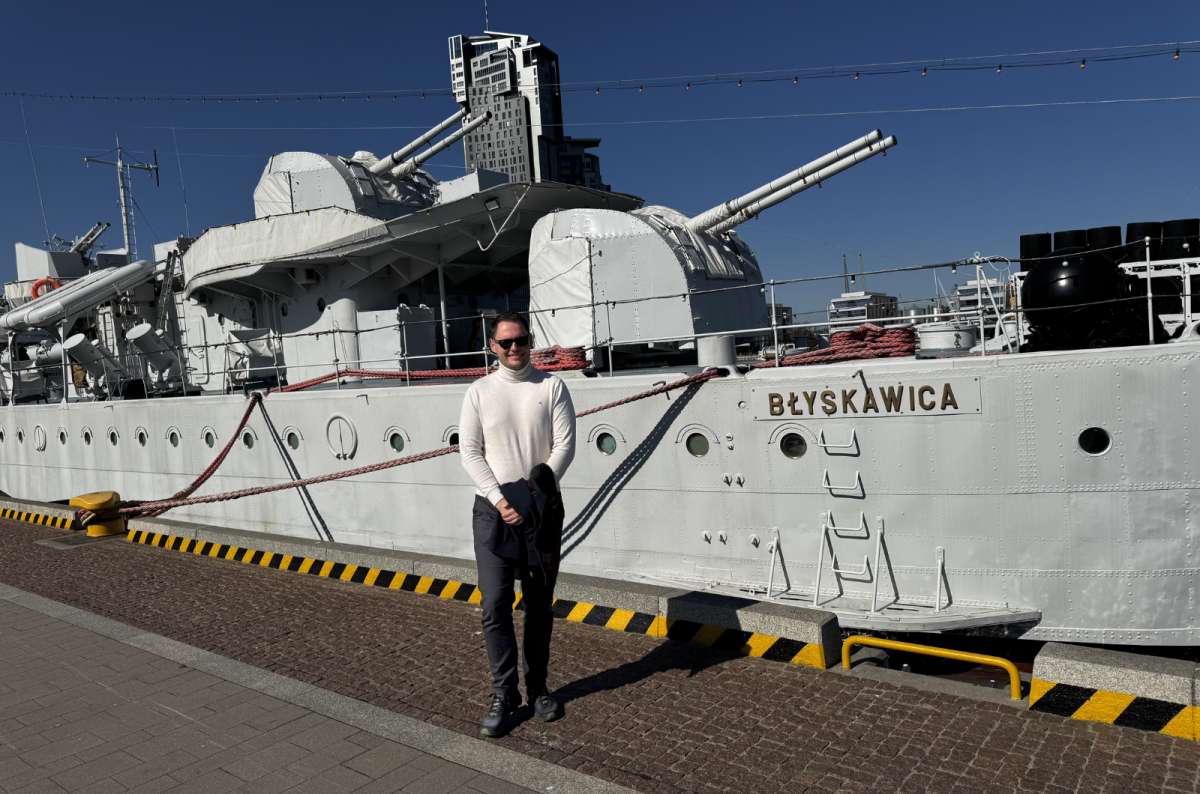 a photo of a tourist posing in front of a ship called Blyskawica at the Gdynia port, Poland, photo by Next Level of Travel