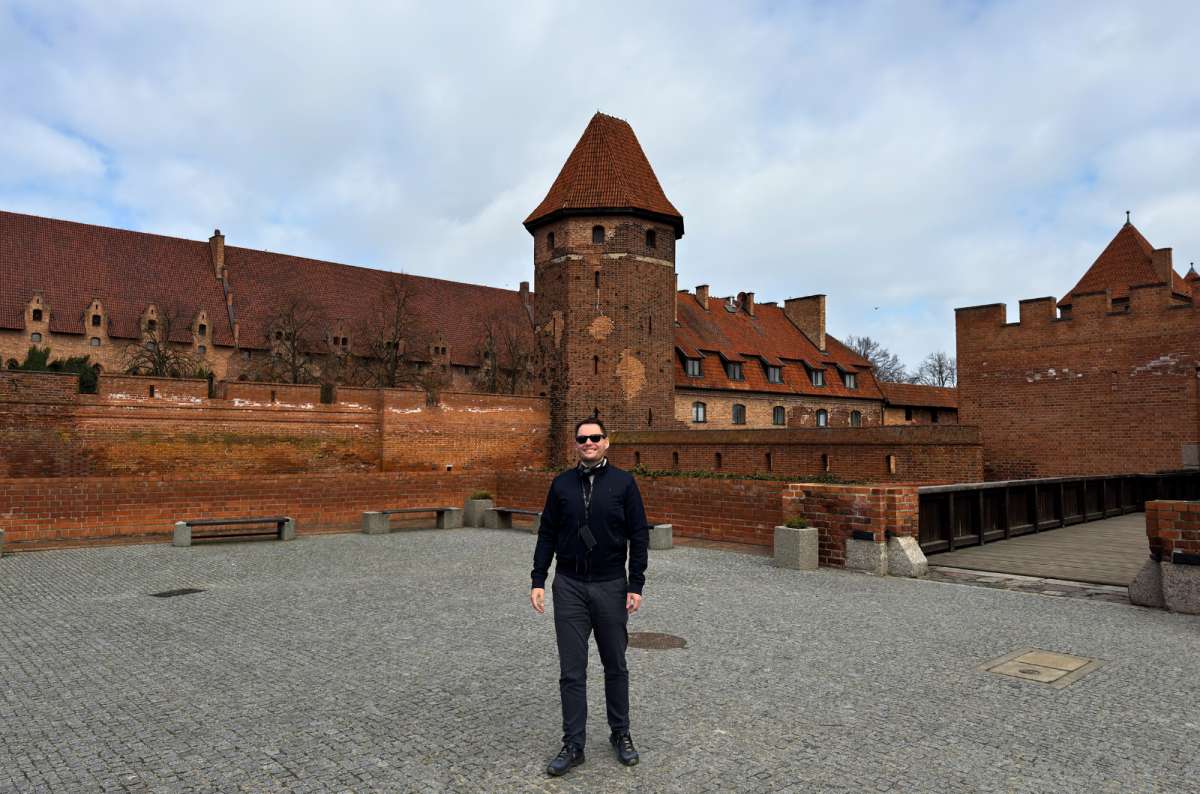 Visitor standing in the courtyard of Malbork Castle, Malbork, Poland, the largest castle in the world, one of the most unique things to do in Poland, photo by Next Level of Travel