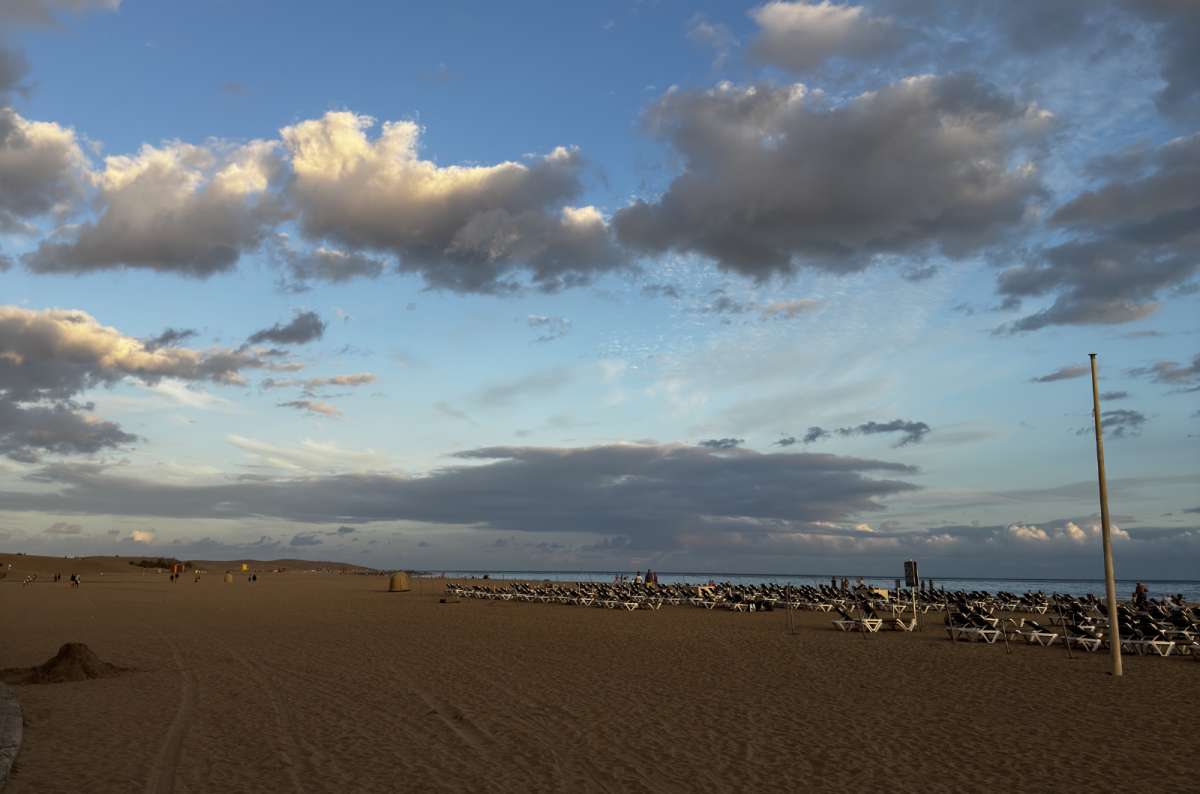 a photo of a beach in Maspalomas with many people and beach chairs visible in the background, Canary Islands, photo by Next Level of Travel