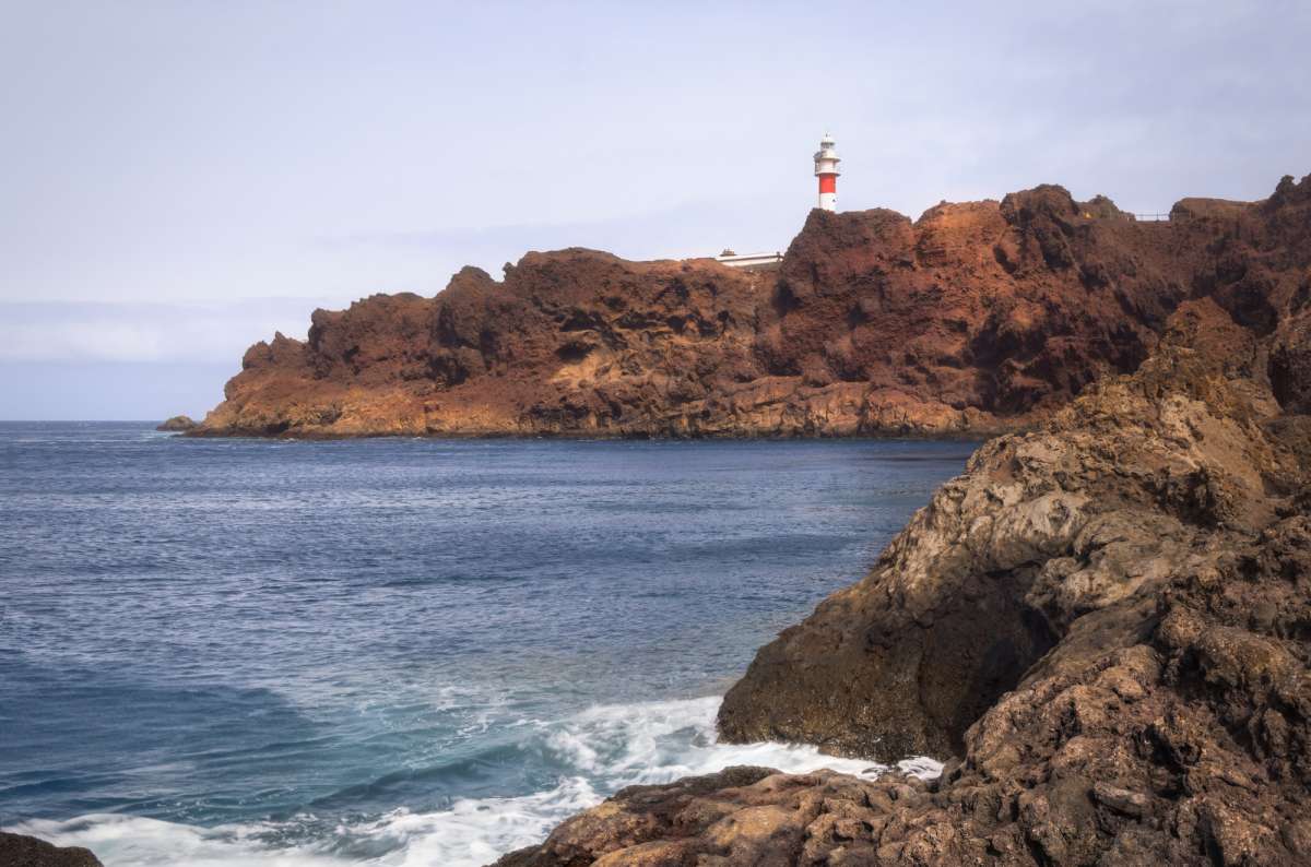 a photo of the lighthouse at Punta de Teno with the ocean hitting the cliffs down below, Canary Islands