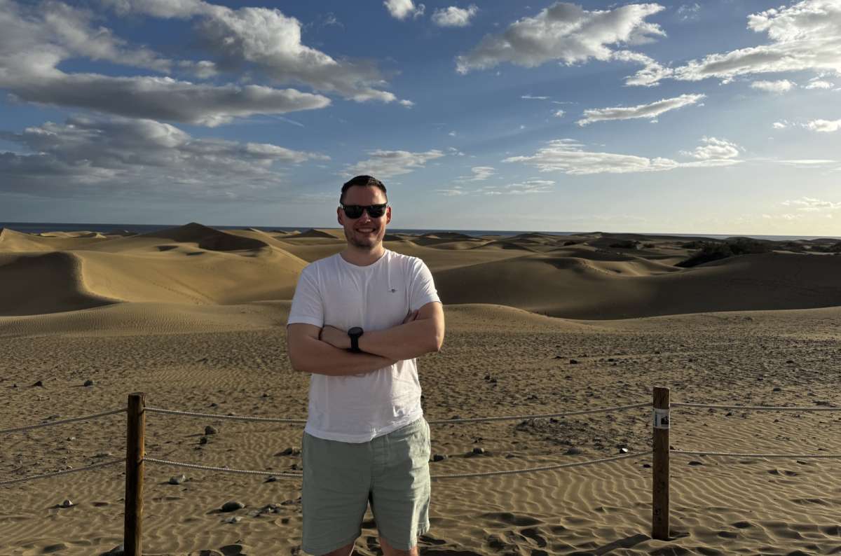  a photo of a tourist posing in front of the Maspalomas sand dunes in Gran Canaria, Canary Islands, photo by Next Level of Travel