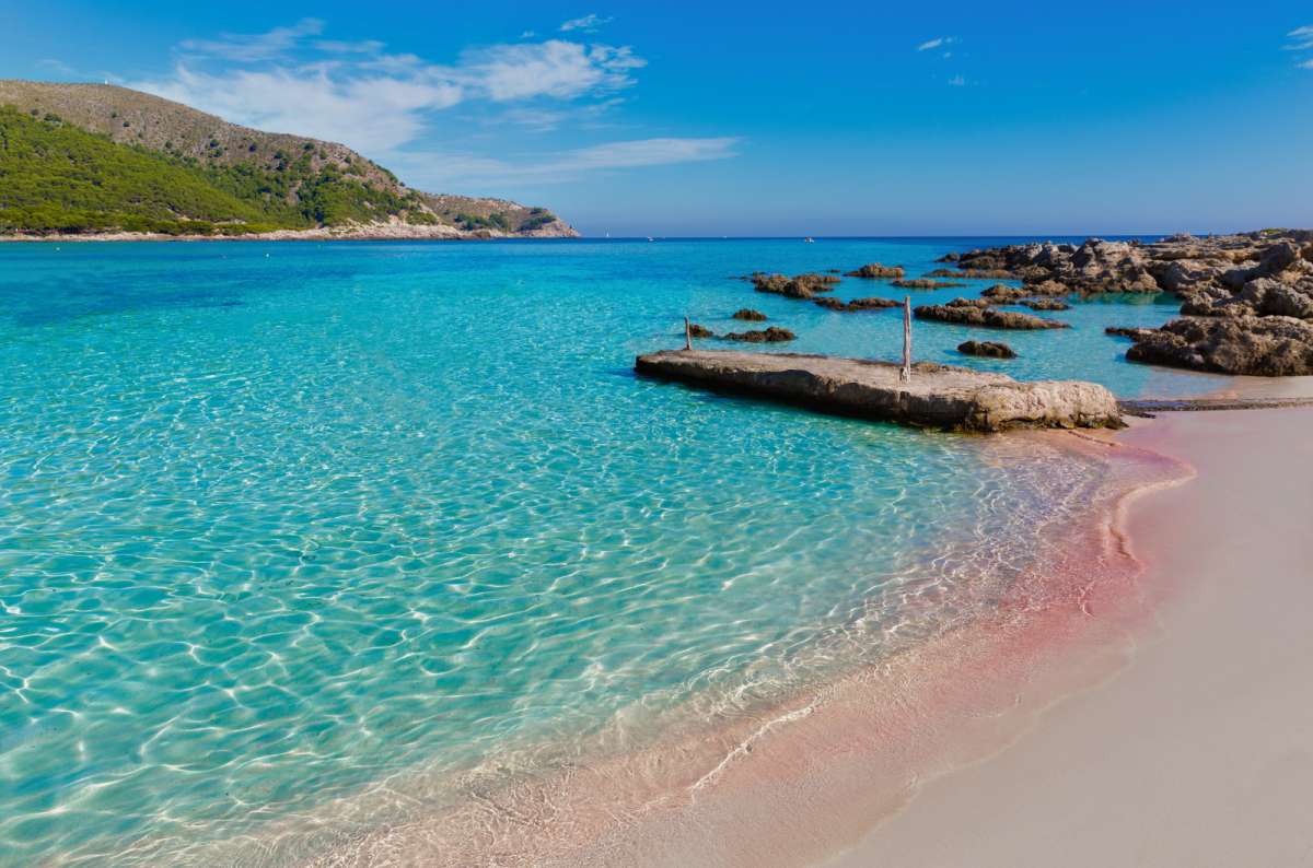 a photo of Güigüi Beach showing the crystal blue waters and the mountains visible in the background, Canary Islands