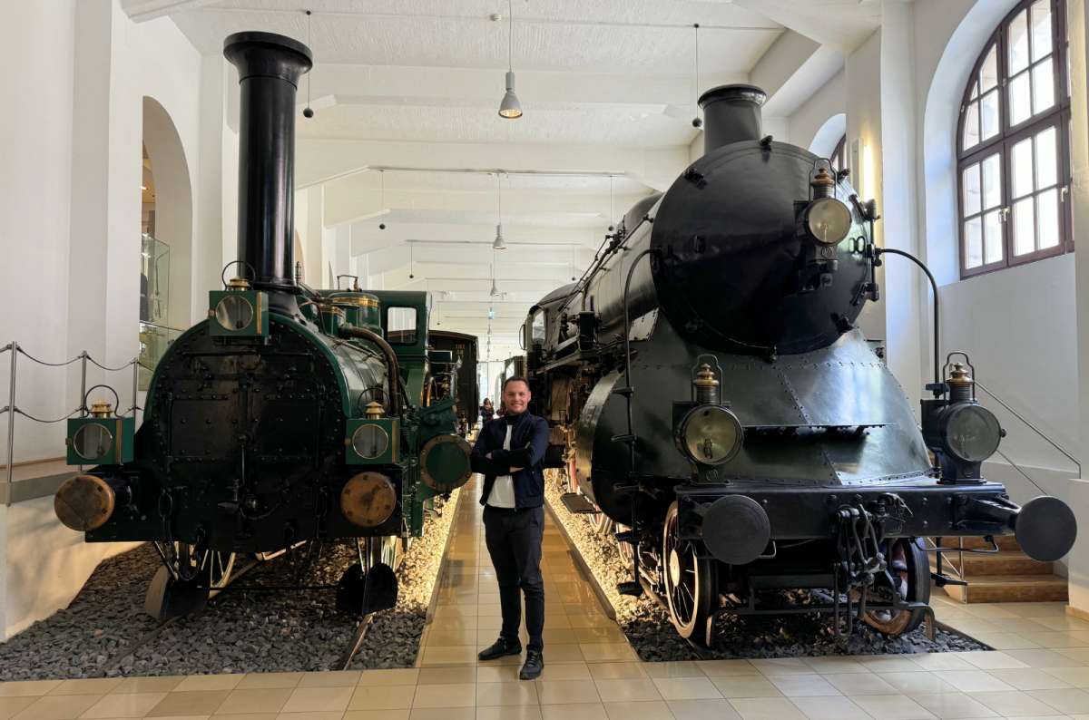 a photo of a tourist posing among trains at the Railway Museum in Nuremberg, Germany, photo by Next Level of Travel