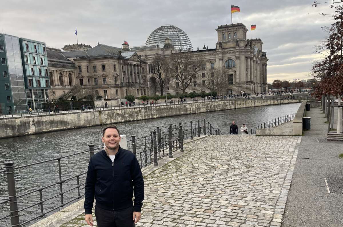 a photo of a tourist walking along the river with the Reichstag Dome visible in the background, Berlin, Germany, photo by Next Level of Travel