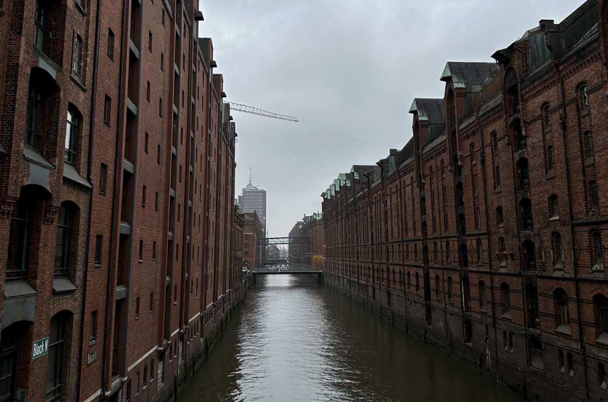 a photo of Speicherstadt showing the canal and characteristic brick building surrounding it, Hamburg, Germany, photo by Next Level of Travel