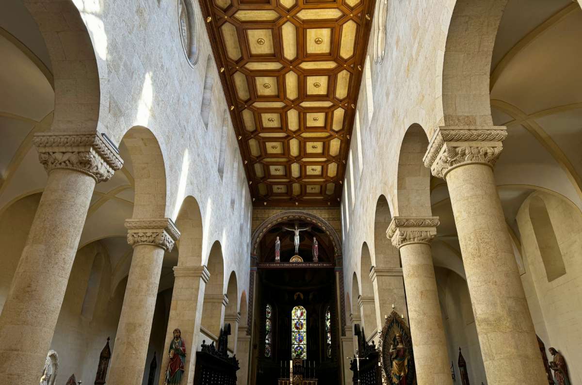 Interior of St. Peter’s Cathedral in Regensburg, Germany, with Romanesque columns and wooden ceiling, photo by Next Level of Travel