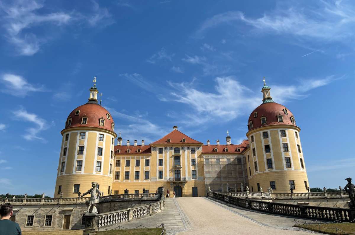 Moritzburg Castle near Dresden, Germany, with yellow Baroque facade and twin towers under a blue sky, photo by Next Level of Travel