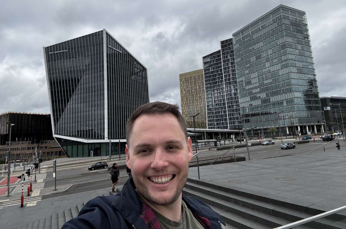 a photo of a tourist taking a selfie in the Kirchberg business district, with glass skyscrapers visible in the background, Luxembourg, photo by Next Level of Travel