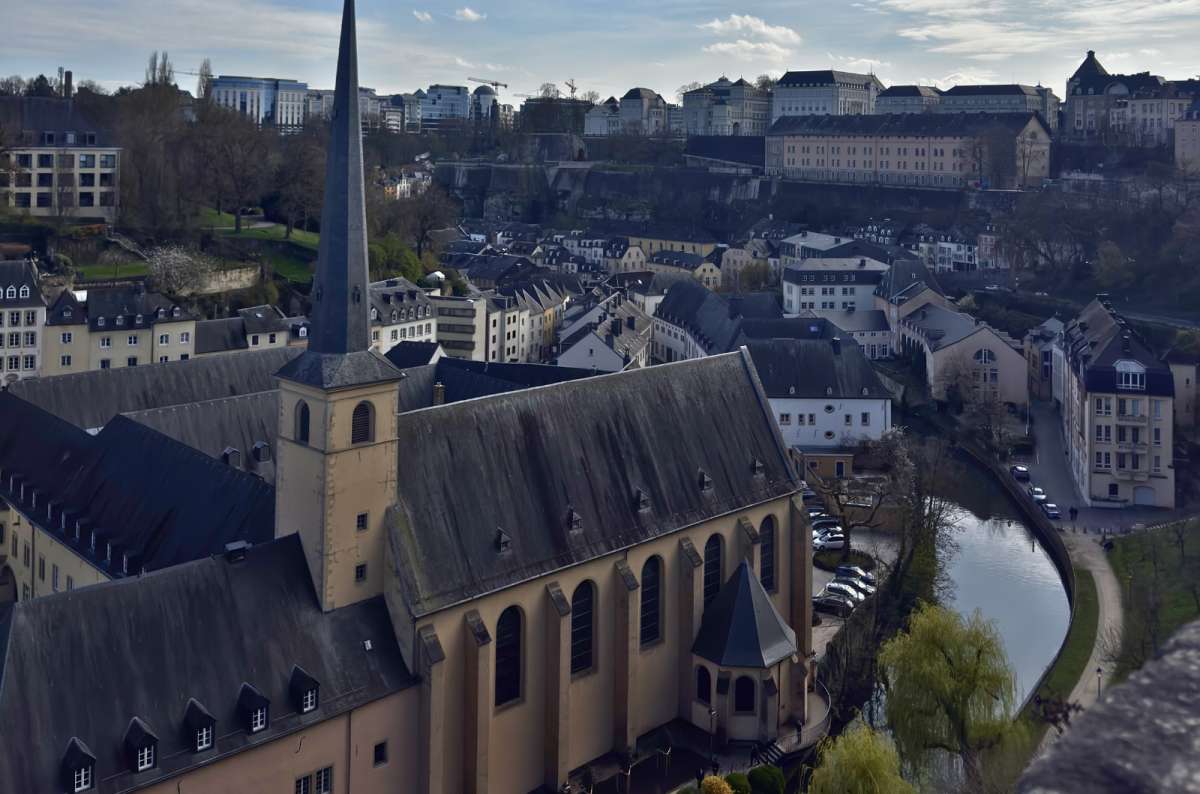 a view of Luxembourg City and the Neumünster Abbey from up above, showing the river Alzette flowing through the city, Luxembourg, photo by Next Level of Travel