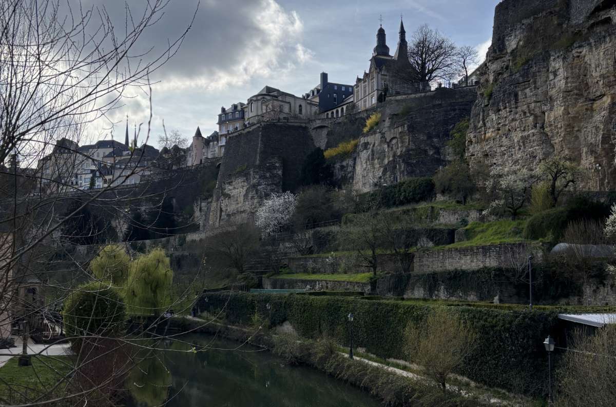 a view of the mountain with the upper city rising above the Alzette river as you stroll along the riverbank in Grund, Luxembourg, photo by Next Level of Travel