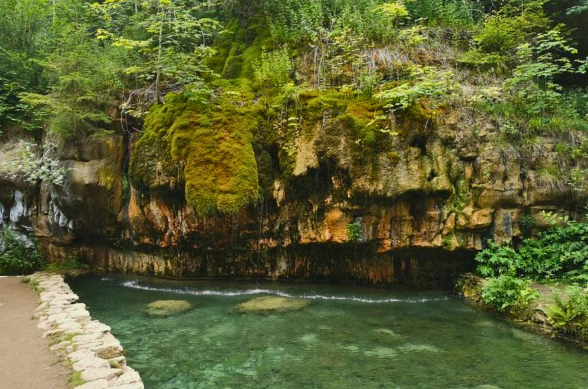 Moss-covered rock formation and clear stream in Müllerthal, Luxembourg, one of the country's best hiking regions