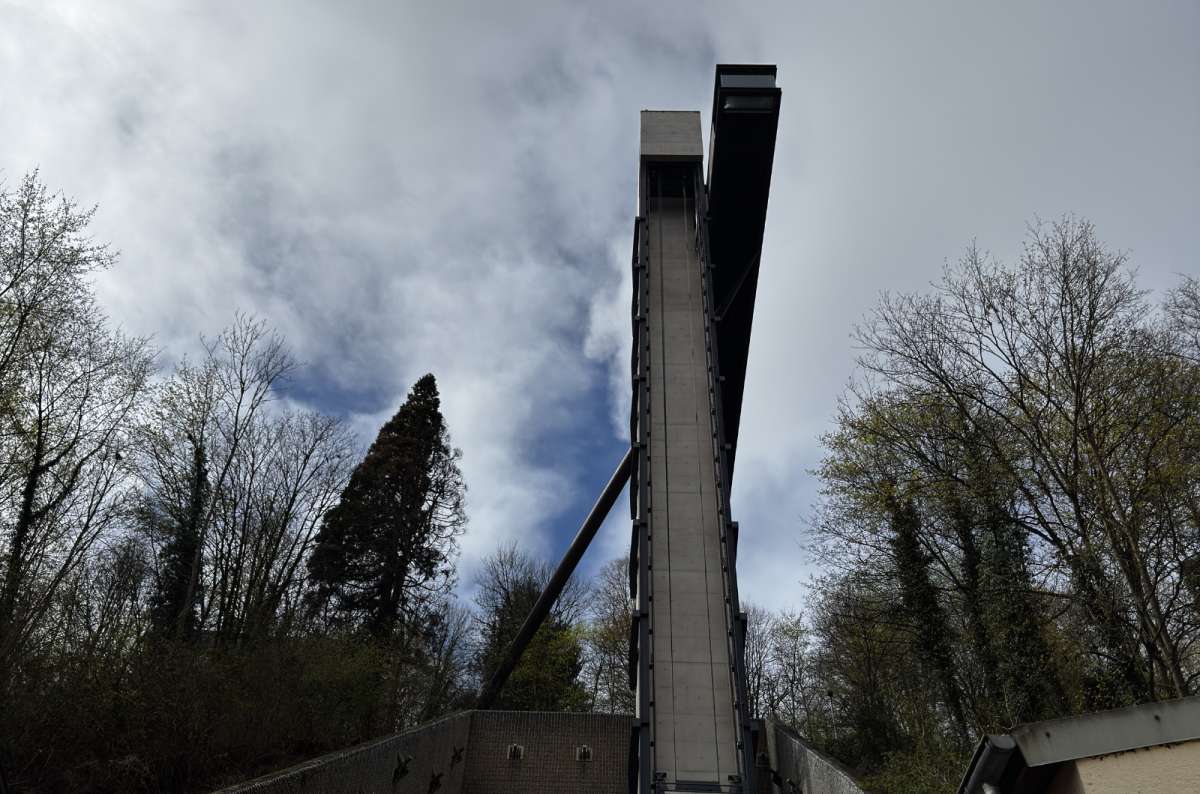 The Pfaffenthal elevator seen from down below, surrounded by tall trees on the upper level, Luxembourg, photo by Next Level of Travel