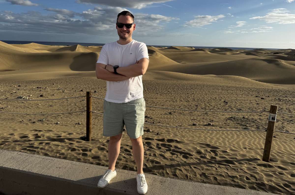 a tourist standing at the edge of the Maspalomas Dunes with the Atlantic Ocean visible in the background, Gran Canaria, Canary Islands, photo by Next Level of Travel