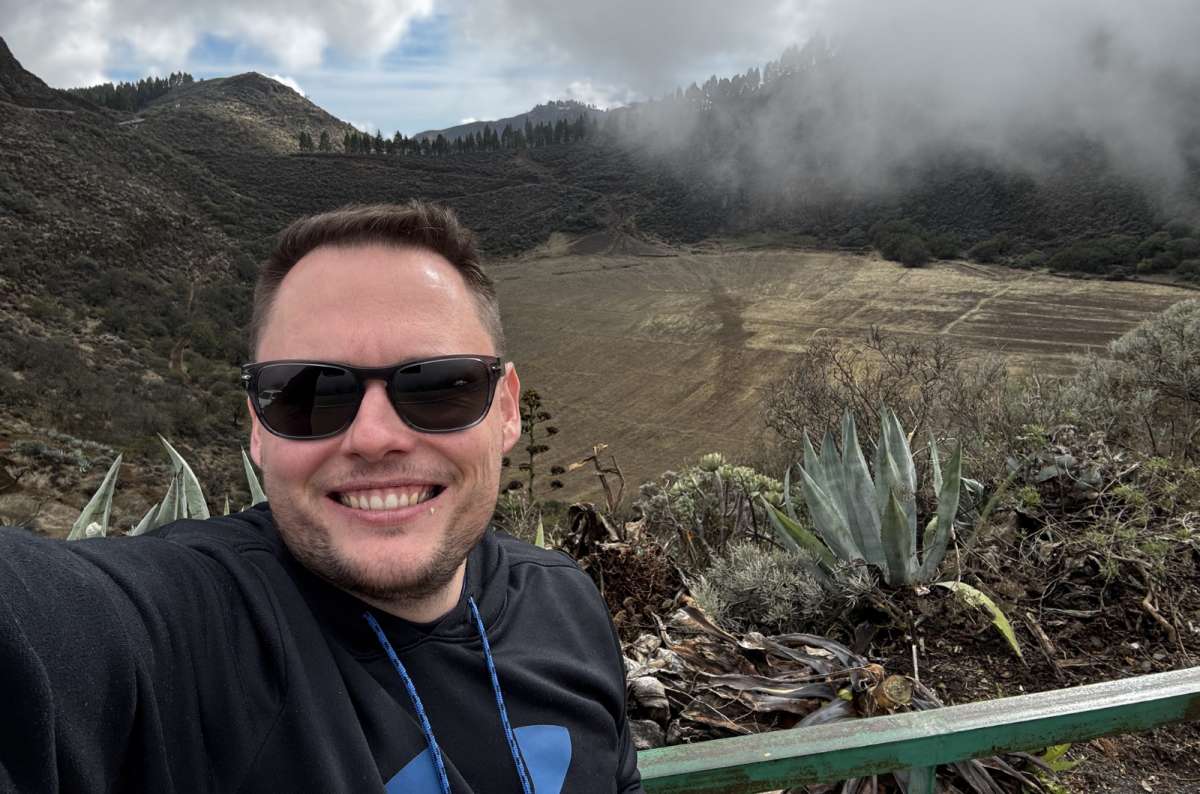 a tourist taking a selfie at the Mirador de los Marteles volcanic crater with clouds rolling into the crater below, Gran Canaria, Canary Islands, photo by Next Level of Travel