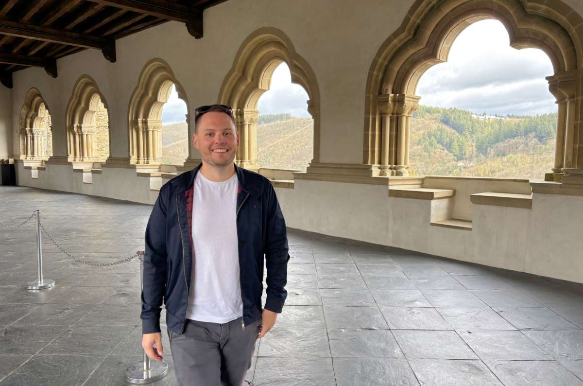 Person standing in the Romanesque gallery of Vianden Castle overlooking the Luxembourg countryside, photo by Next Level of Travel