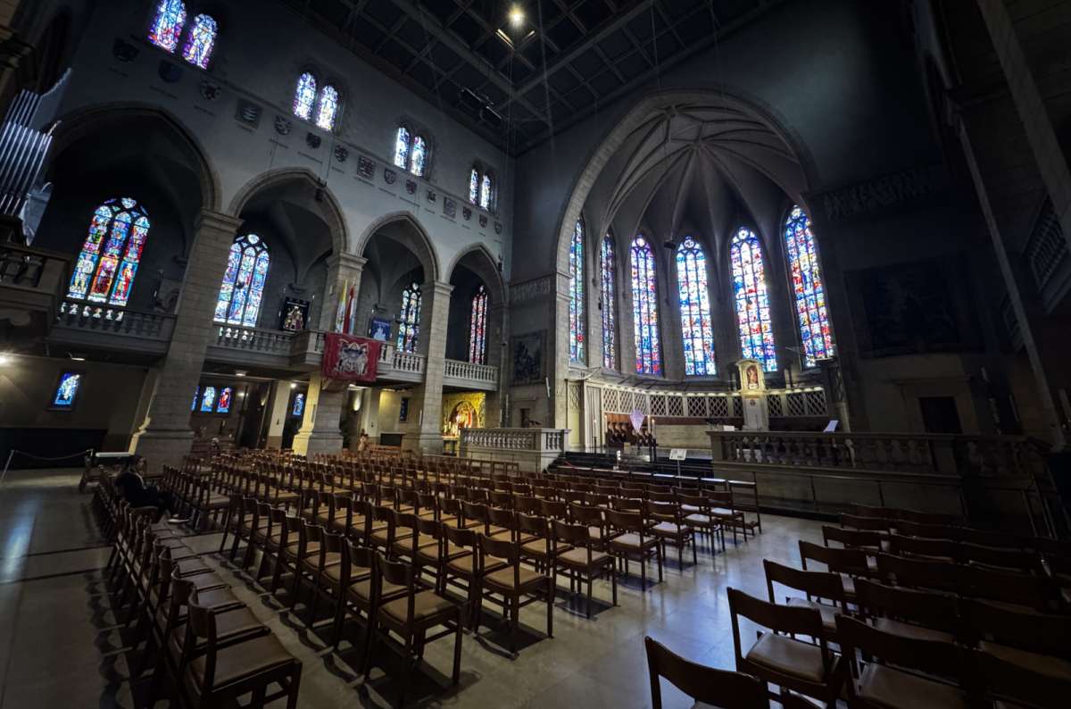 Stained-glass windows and the vaulted apse above rows of wooden chairs inside Notre Dame Cathedral, Luxembourg City, Luxembourg, photo by Next Level of Travel 