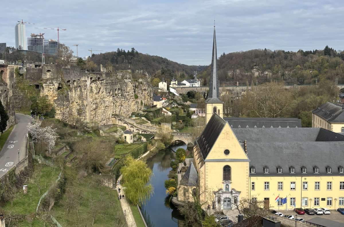 Yellow houses and the Alzette river in the Grund lower town framed by cliffs, Luxembourg City, Luxembourg, photo by Next Level of Travel 