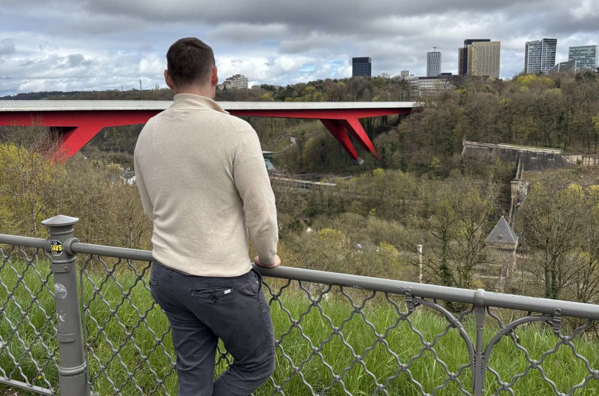 A tourist at a viewpoint with the red Grand Duchess Charlotte Bridge behind, Luxembourg City, Luxembourg, photo by Next Level of Travel