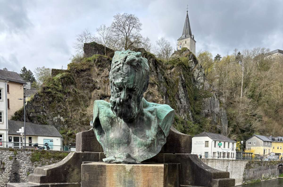 The bronze Victor Hugo bust with Vianden town and castle behind, Vianden, Luxembourg, photo by Next Level of Travel