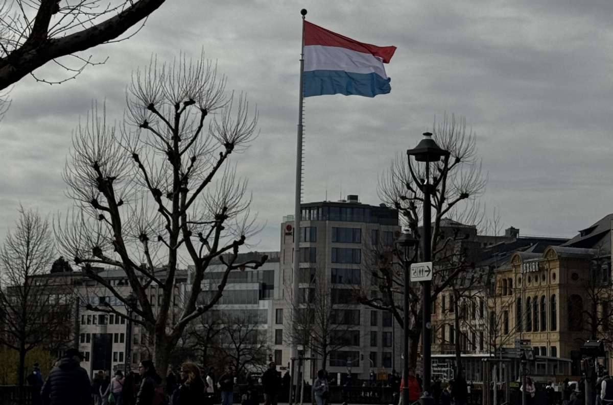 The Luxembourg flag on a pole above a square with bare trees, Luxembourg City, Luxembourg, photo by Next Level of Travel