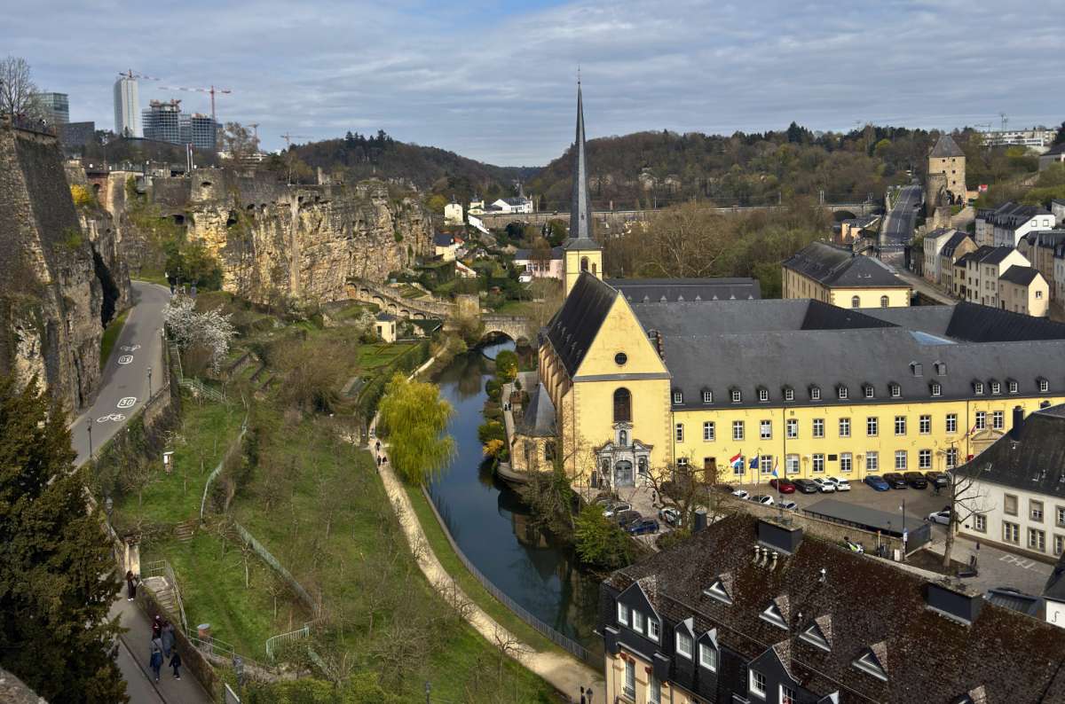 a photo of the Neumünster Abbey and the Grund district in the Alzette valley seen from the Corniche, Luxembourg City, photo by Next Level of Travel