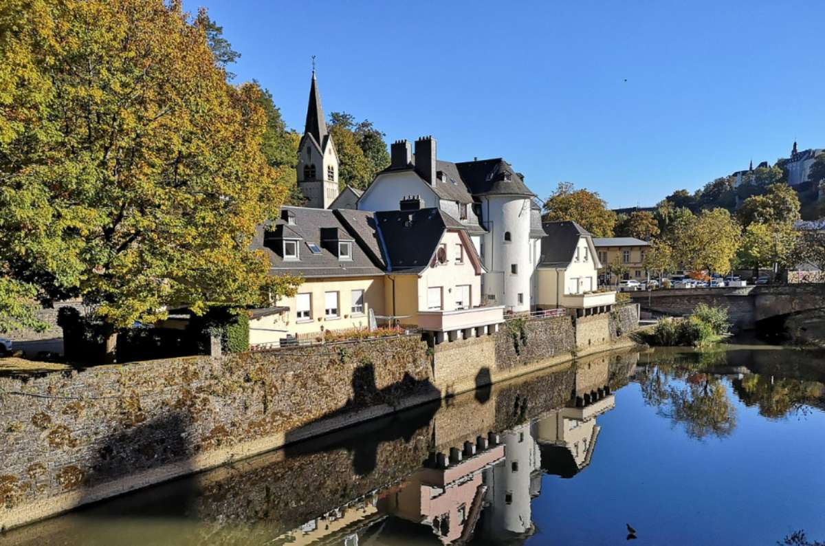 Colorful houses and St. Nicholas Church reflected in the Our River in Vianden, Luxembourg