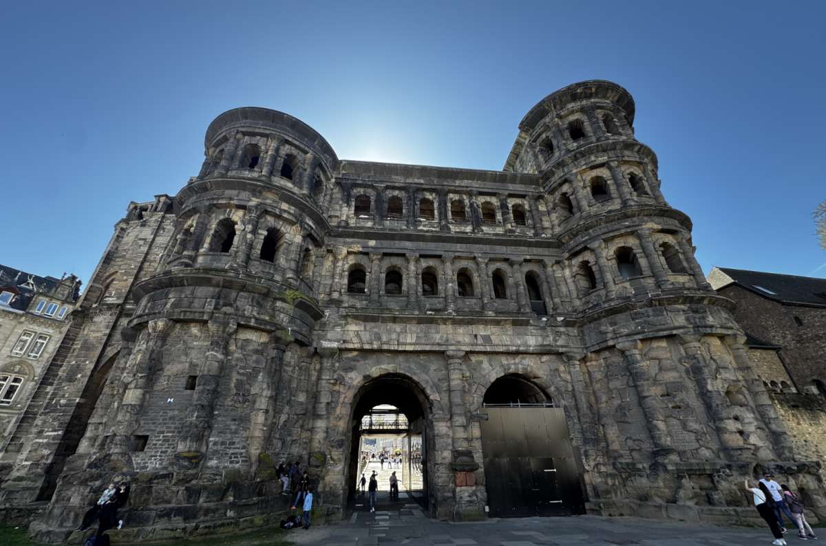 a photo of the Porta Nigra Roman gate under a clear blue sky in the old town, Trier, Germany, photo by Next Level of Travel