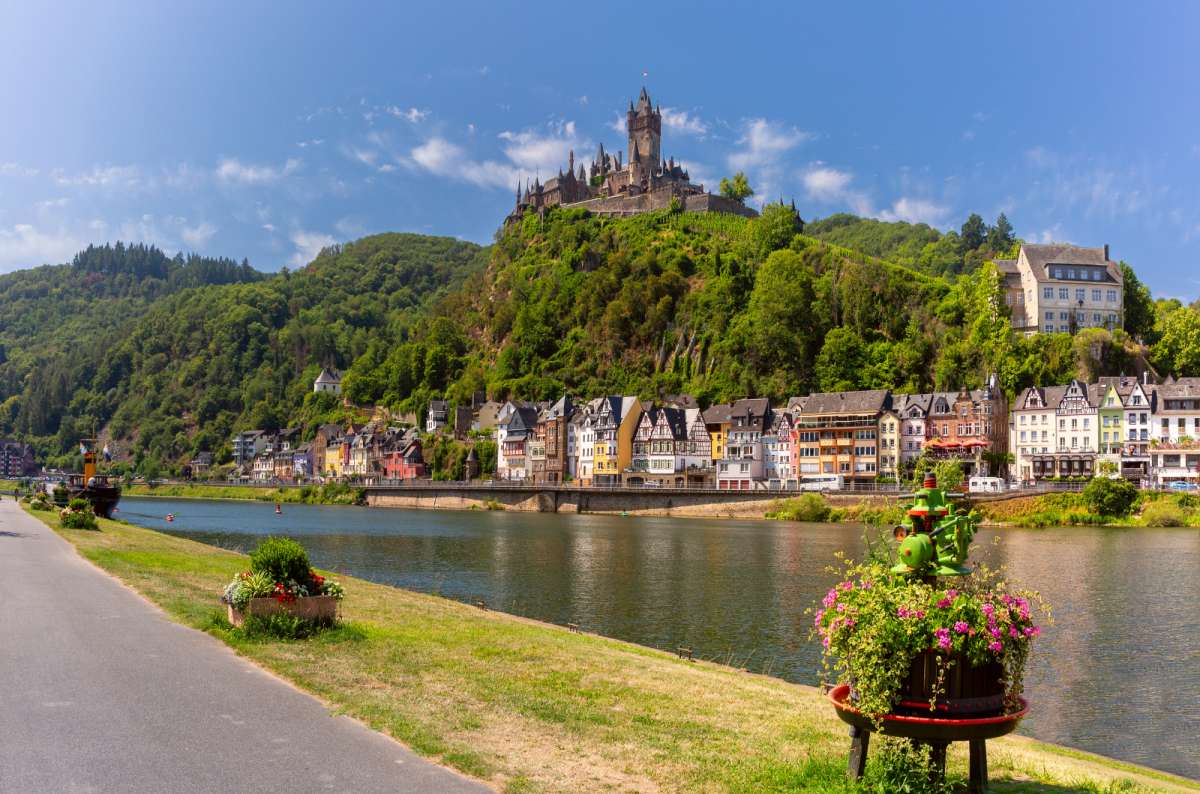 a photo of the riverfront town of Cochem with its half-timbered houses and the imperial castle on a vine-covered hill above, Moselle, Germany
