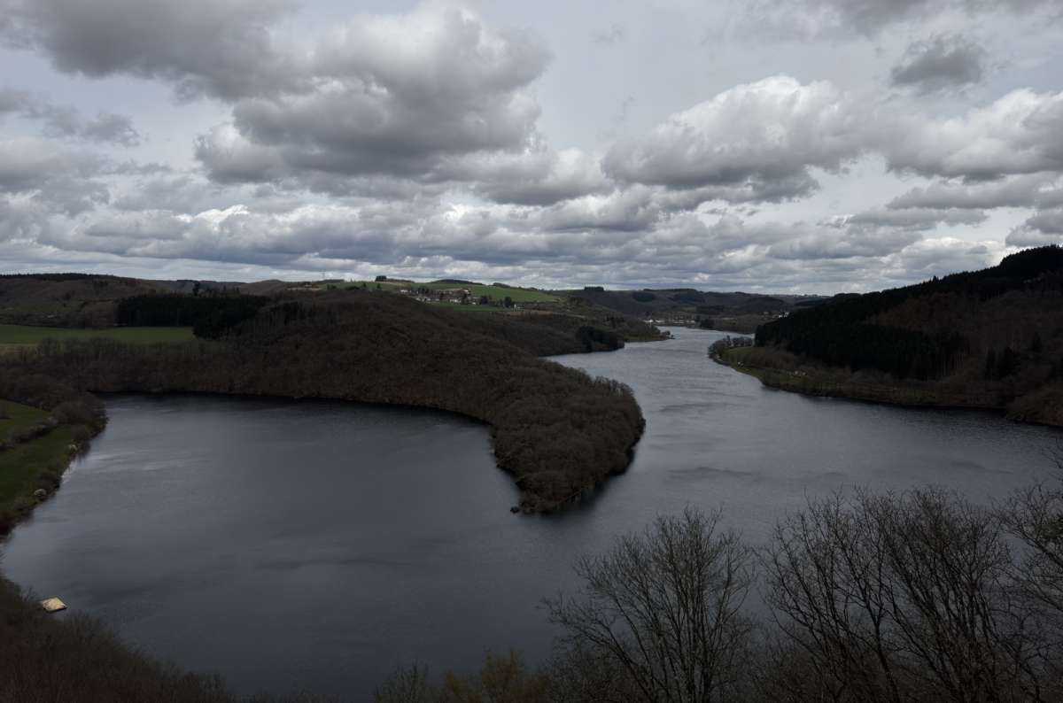 a photo of the Upper Sûre lake curving through forested hills, Upper Sûre, Luxembourg, photo by Next Level of Travel