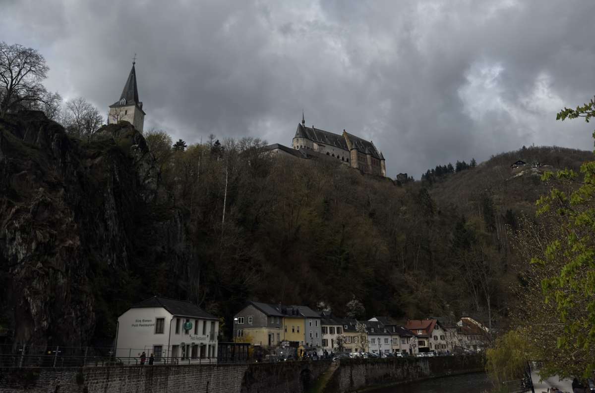 a photo of Vianden Castle perched on a forested rock above the town and the Our river, Vianden, Luxembourg, photo by Next Level of Travel