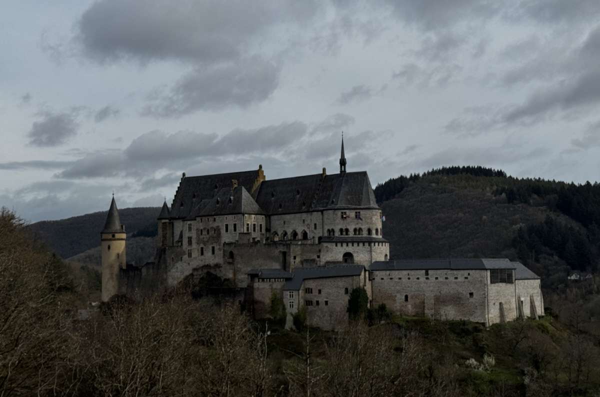 a photo of Vianden Castle stretched along its ridge above the wooded valley, Vianden, Luxembourg, photo by Next Level of Travel 